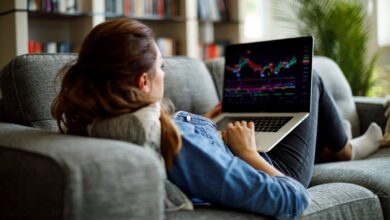 Person on couch looking at stock chart on laptop