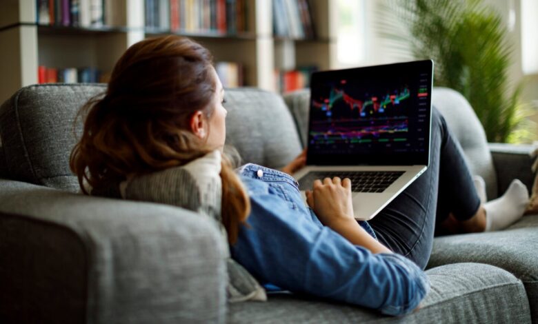 Person on couch looking at stock chart on laptop